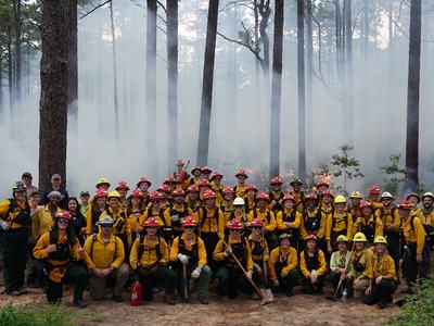 Group photo of Fire Week participants in front of a prescribed burn at North Carolina State Parks.