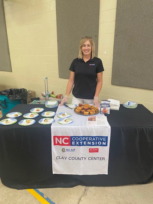 A woman stands at the N.C. Cooperative Extension booth, showing a healthy muffin makeover.