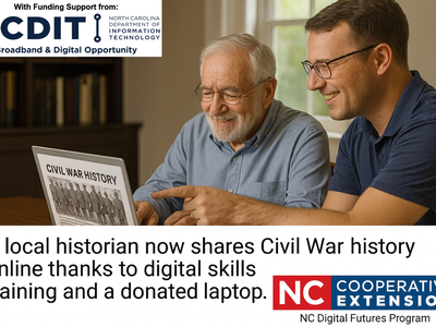 Two men look at a laptop together.
