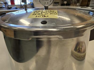 A pressure cooker with a note on top about the pressure weight.