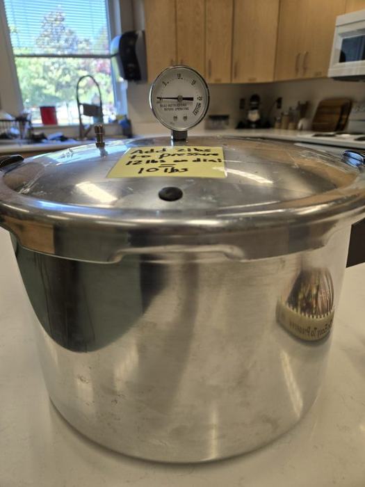 A pressure cooker with a note on top about the pressure weight.