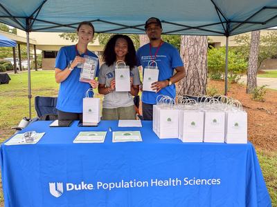 Duke Population Health Services team poses with gift bags at an event table.