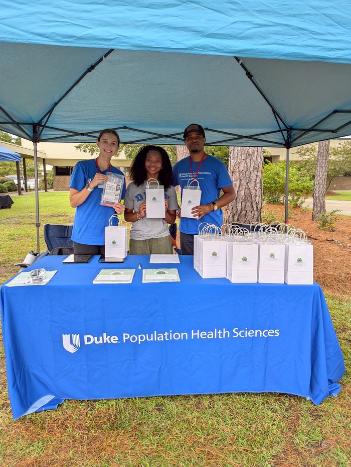 Duke Population Health Services team poses with gift bags at an event table.