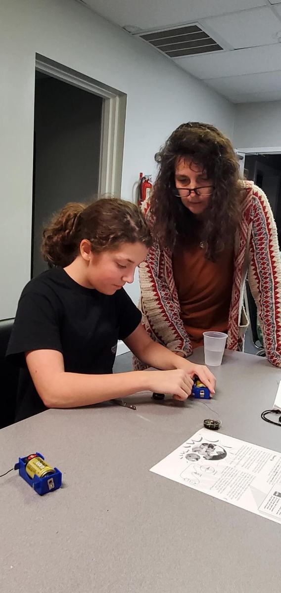 4-H youth working on an electric project as her 4-H club leader observes.