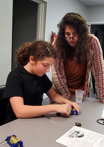 4-H youth working on an electric project as her 4-H club leader observes.