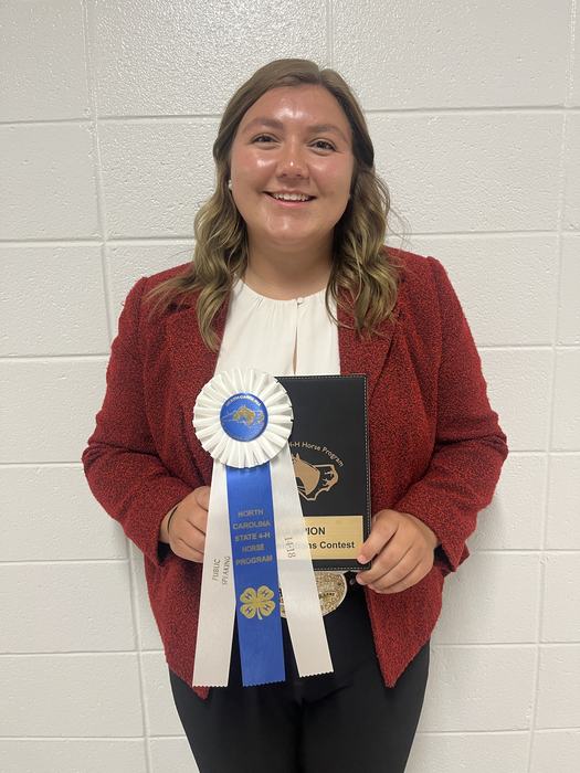 Person holding blue-and-white ribbon reading "North Carolina State 4‑H Horse Program" and a plaque