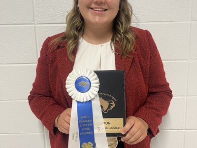 Person holding blue-and-white ribbon reading "North Carolina State 4‑H Horse Program" and a plaque