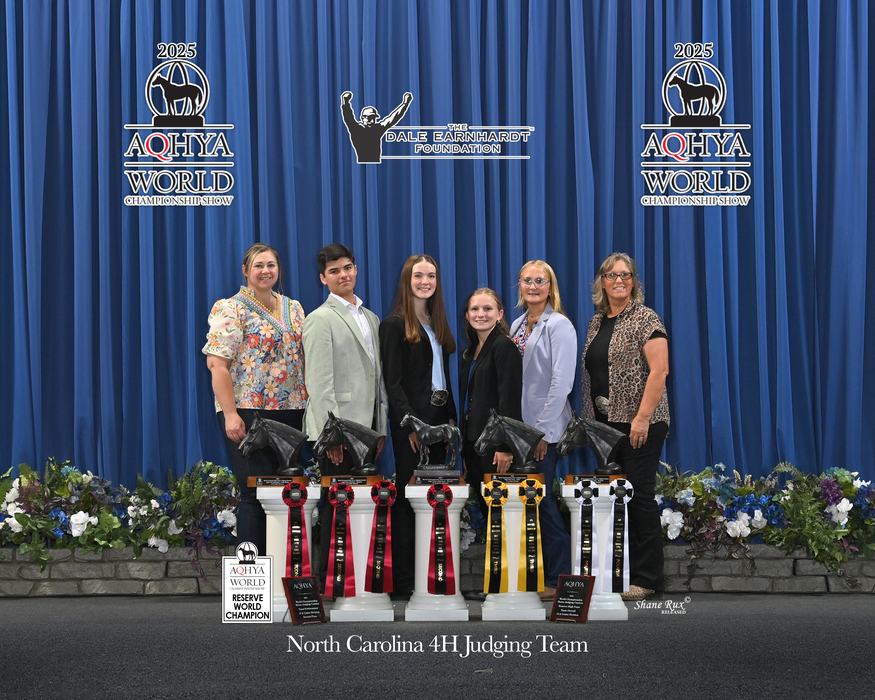 Six-person North Carolina 4H judging team standing behind horse trophies and ribbons
