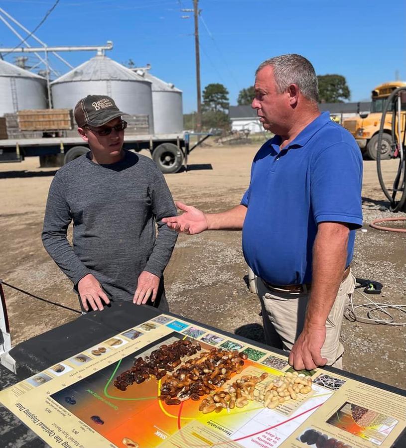 Two men look at pod maturity using a pod maturity graph.