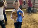 A girl poses with her chicken and a blue ribbon.