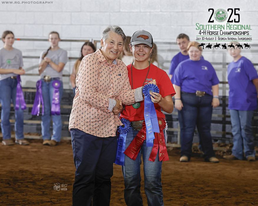 Woman shaking hands with youth holding blue ribbons at 2025 4-H Horse Championships