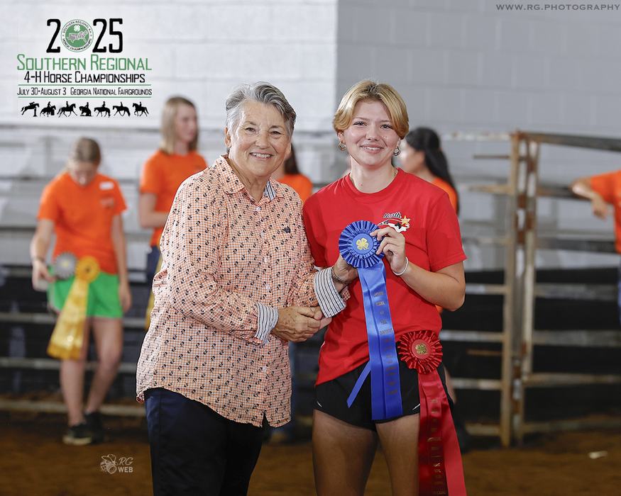 Two people holding a blue ribbon at 2025 Southern Regional 4-H Horse Championships.