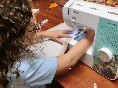 Young person guiding fabric through a Brother sewing machine