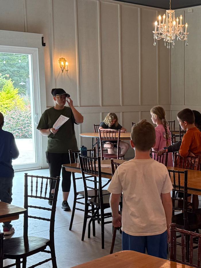 Children in a dining room work around tables.