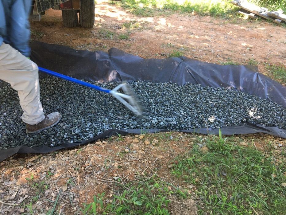 Raking a ditch filled with gravel.