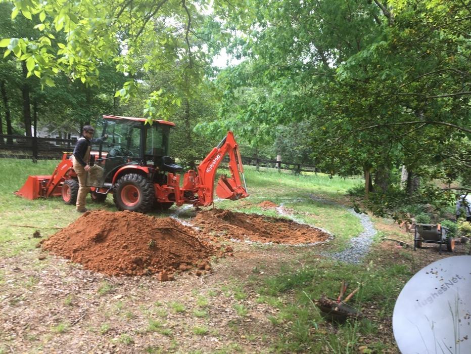 A backhoe digging a water detention pond.