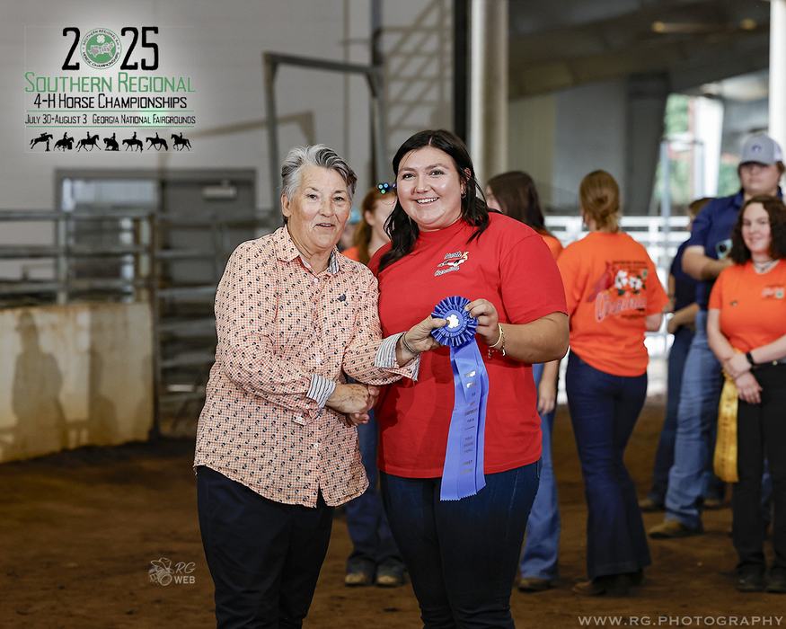 Woman receives blue ribbon while shaking hands at 2025 Southern Regional 4‑H event