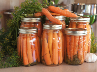 Home canned carrots with raw carrots on top of the cans