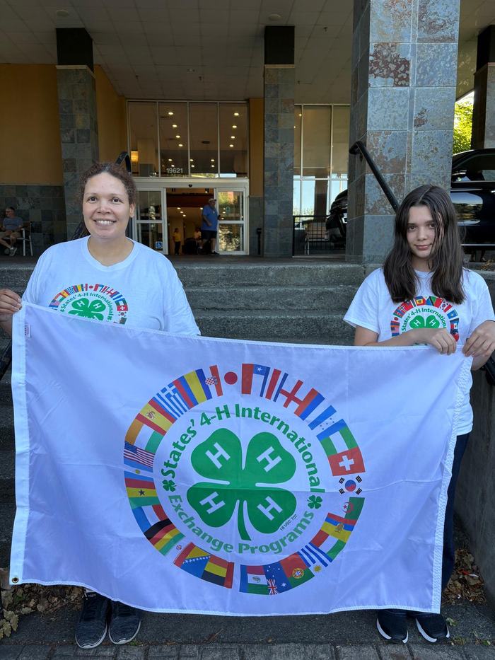 2 females standing in front of colorful flag