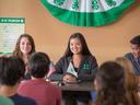 Three youth leaders at table with 4-H flag and small US flag addressing audience
