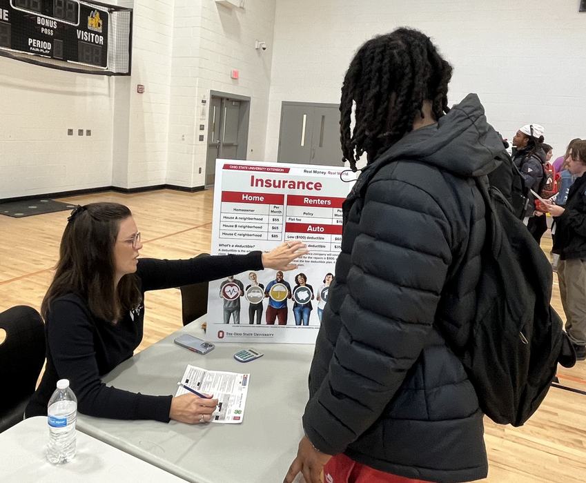 A volunteer goes over types of insurance with a high school student.