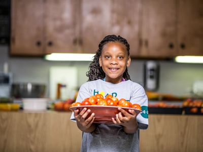 Child carrying platter of tomatoes