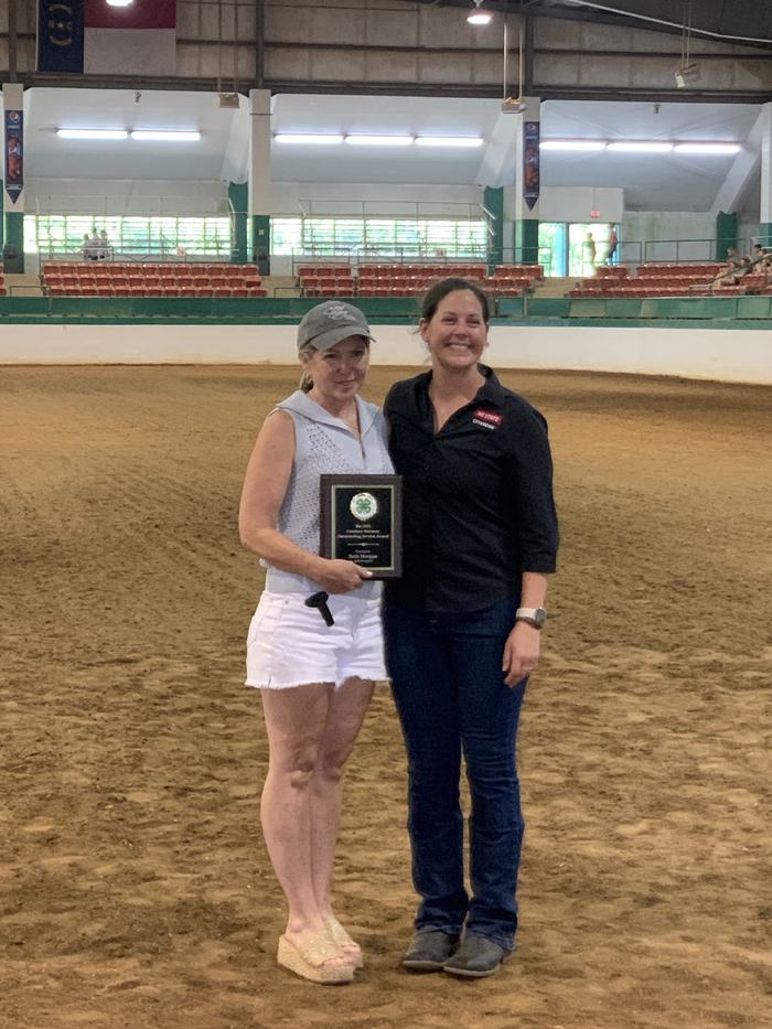 Beth Morgan poses with her award plaque in the middle of an arena.