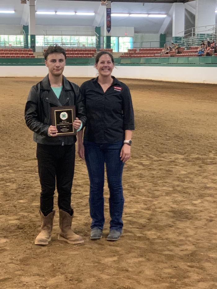 Blake Garber poses with his award plaque in the middle of an arena.