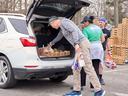 Volunteers loading groceries into open SUV trunk at distribution; shirt reads "PORCH"