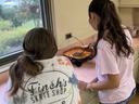 Two youth standing at a counter, cooking together in a Chopped! International 4-H class, preparing a recipe from another country.