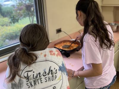 Two youth standing at a counter, cooking together in a Chopped! International 4-H class, preparing a recipe from another country.