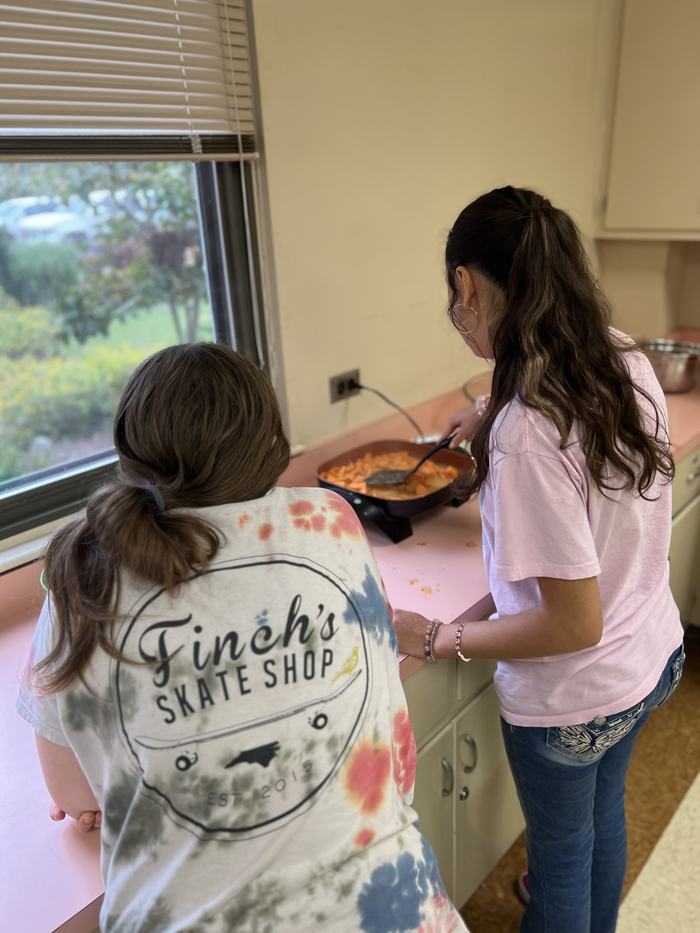 Two youth standing at a counter, cooking together in a Chopped! International 4-H class, preparing a recipe from another country.