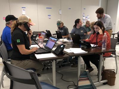Group of people working at laptops and phones in an office after Hurricane Helene.