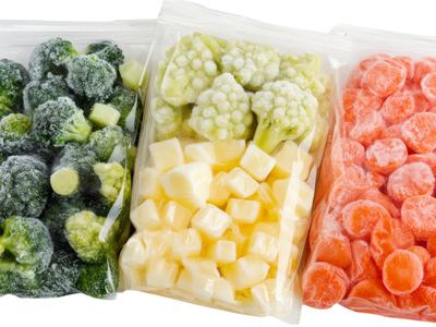 Frozen broccoli, cauliflower, and chopped carrots are stored in plastic bags