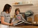Adult and child on a kitchen counter looking through an open cookbook