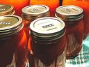 Mason jars of orange tomato sauce on a towel, metal lids labeled "2020"