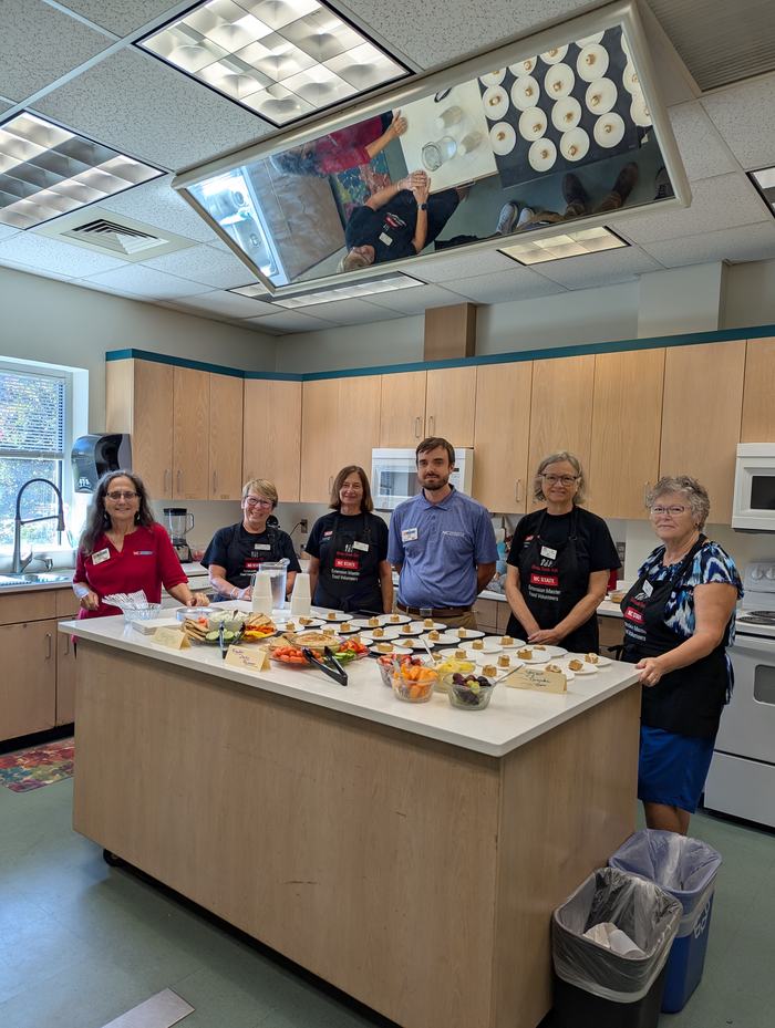 Volunteers stand in a teaching kitchen.