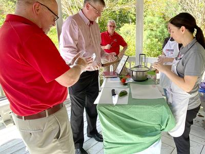 Onslow County EFNEP Educator (Paige S.) showing Dean Fox and Extension Director David Monks the pitch grip technique.