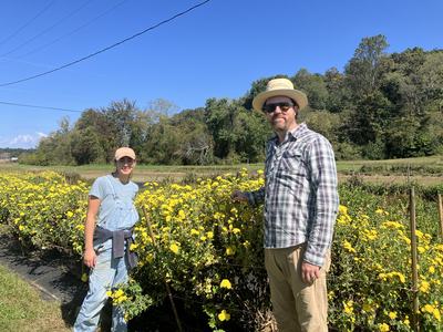 A young man and woman standing in a field of bright yellow flowers