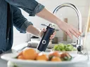 Person filling water bottle at sink.