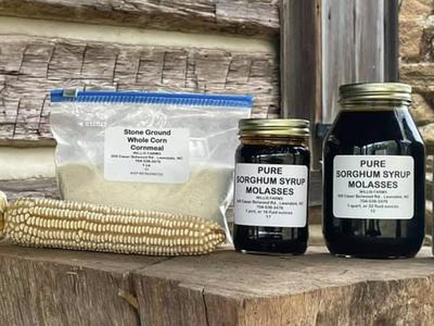 Dried corn ear, bag labeled "Stone Ground Whole Corn Cornmeal" and jars labeled "Pure Sorghum Syrup"
