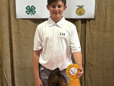 Boy (132) at Coastal Plains Chicken Show holding fourth-place ribbon and a chicken