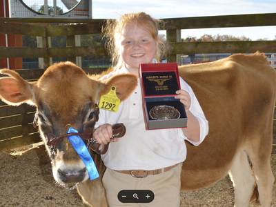 A girl poses with her heifer and an award.