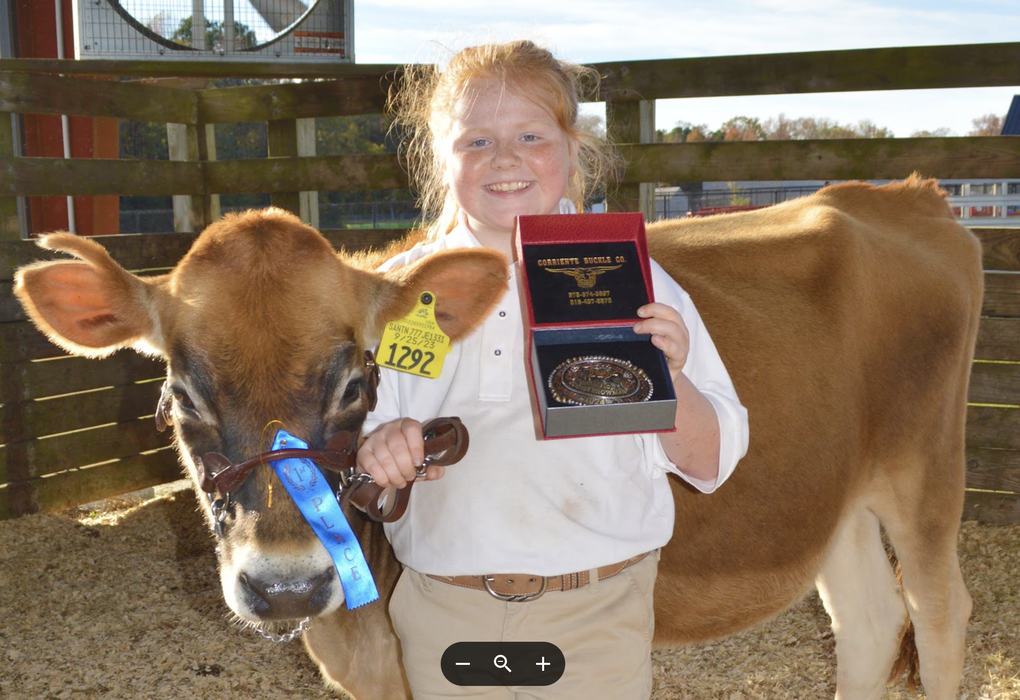A girl poses with her heifer and an award.