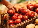 picture of someone picking out apples and potatoes from baskets