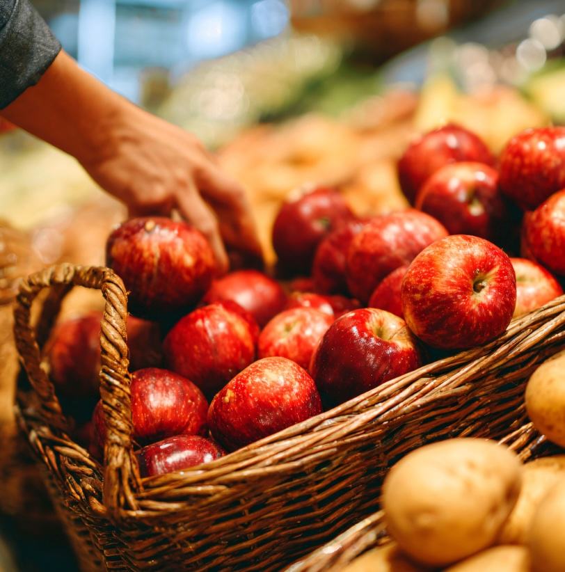 picture of someone picking out apples and potatoes from baskets