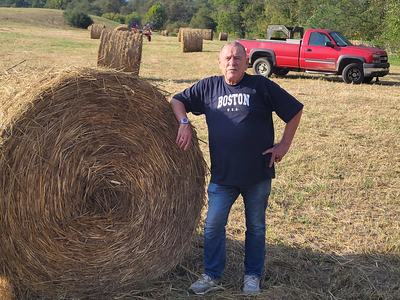 Field with hay equipment and round hay bales