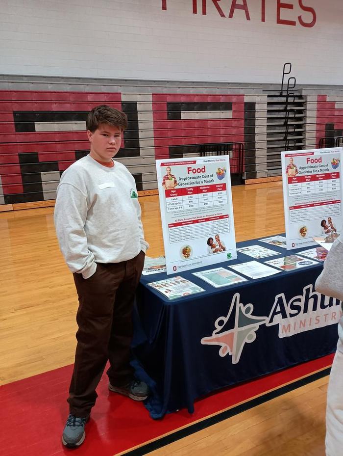 boy standing next to a table of information