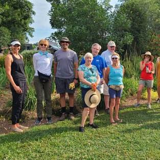 Group of adults standing in grass posing for group photo.
