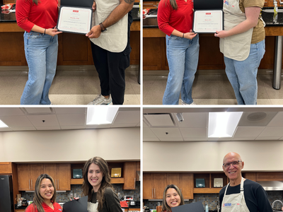 Woman in red handing framed certificates to four different people in a kitchen setting